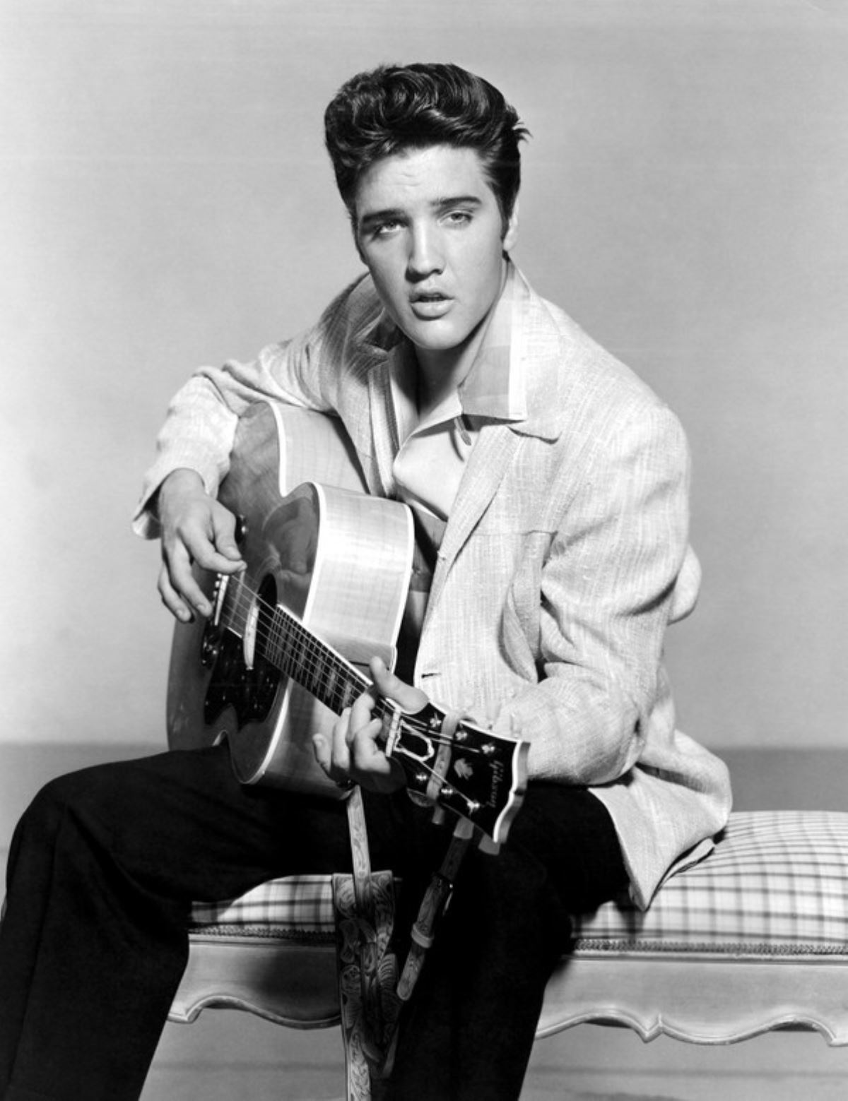 <p><strong>5. Gitar çalmayı kendi kendine öğrendi</strong></p>
<p>1945'te 10 yaşındaki Elvis, yerel radyo istasyonunda canlı yayınlanan Tupelo'da bir gençlik yetenek yarışmasına katıldı. Bu Elvis'in halka açık ilk performansıydı. Beşinci oldu. </p>
<p>Aynı yıl, ailesi, Elvis'in istediği ancak çok pahalı olduğu anlaşılan bir bisiklet yerine, doğum gününde ona bir <strong>gitar</strong> hediye etti. Elvis kısa sürede kendi kendine gitar çalmayı öğrendi ve bir genç olarak kısa süre sonra okul konserlerinde sahneye çıkmaya ve yerel yetenek yarışmalarına katılmaya başladı.</p>
<p>Bu süre zarfında, ikonik imajının anahtarı olacak bir şekilde sanatçı olarak stilini geliştirmeye başladı: <strong>Küba yakalı gömlekler, pileli pantolonlar ve kuruş mokasenleri</strong> temel giysileri haline geldi. O zamana göre alışılmadık bir şekilde saçlarını da uzun tutmaya başladı. Jöleyle saçlarını geriye yatırdı.</p>