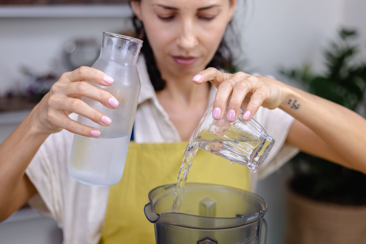 171342642 woman pouring water glass bottle blender kitchen