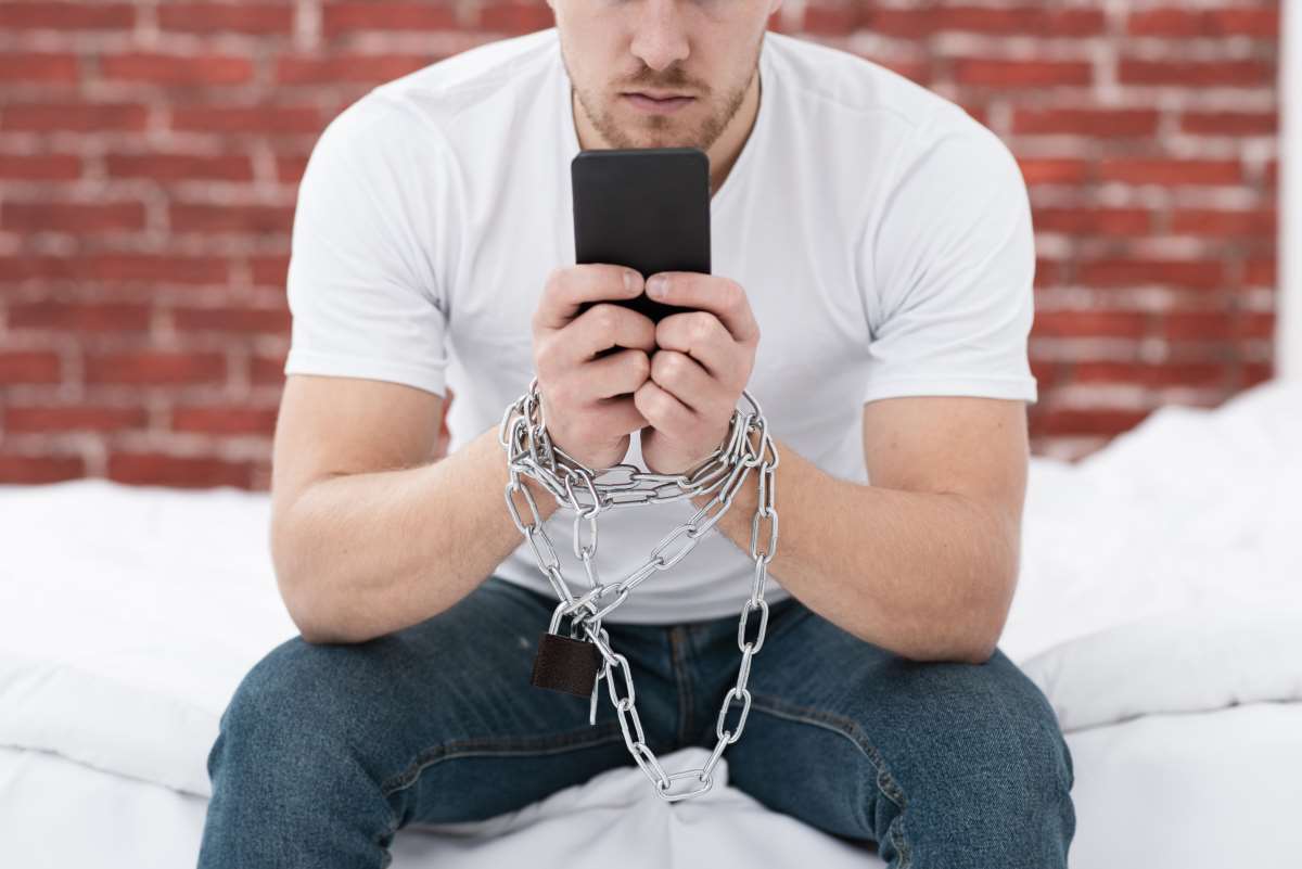 132702124 man holding his phone while he is tied up with chains